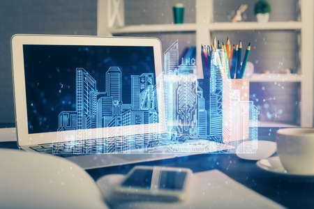 Desktop computer background in office and big town buildings hologram drawing. Double exposure. Smart city concept.の写真素材