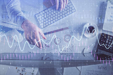 Multi exposure of mans hands typing over computer keyboard and forex graph hologram drawing. Top...