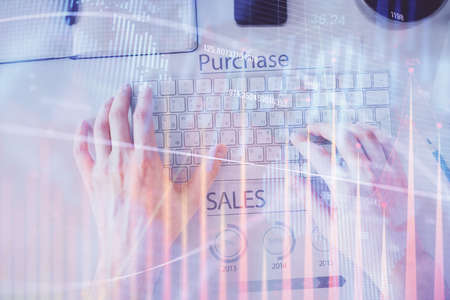Double exposure of mans hands typing over laptop keyboard and forex chart hologram drawing. Top...