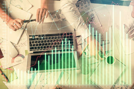 Double exposure of man and woman working together and financial graph hologram. Business concept....