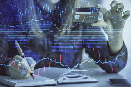 Double exposure of woman on-line shopping holding a credit card and financial graph drawing. Stock...
