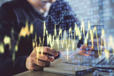 Double exposure of mans hands holding and using a phone and financial graph drawing. Analysis concept.の写真素材