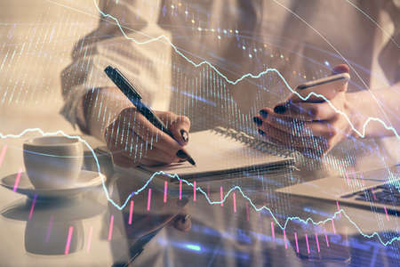 Double exposure of financial graph sketch hologram and woman holding and using a mobile device....