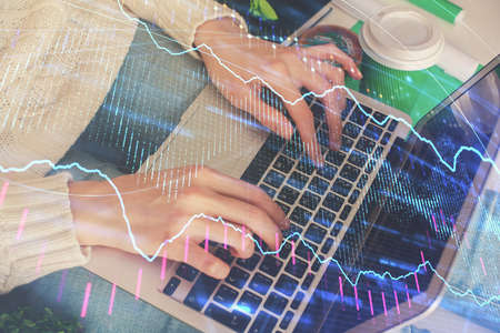 Double exposure of woman hands typing on computer and forex chart hologram drawing. Stock market invest concept.の写真素材