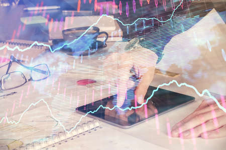 Double exposure of mans hands holding and using a digital device and forex graph drawing. Financial...