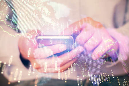 Multi exposure of mans hands holding and using a digital phone and forex graph drawing. Financial...