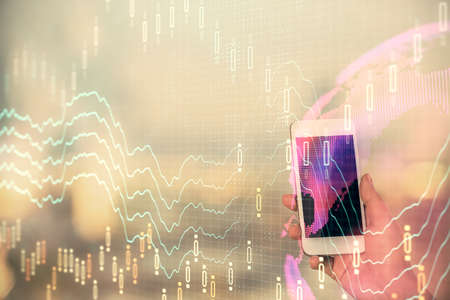 Double exposure of forex chart sketch hologram and woman holding and using a mobile device. Stock...