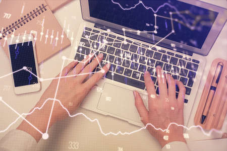 Double exposure of woman hands working on computer and forex graph hologram drawing. Top View....