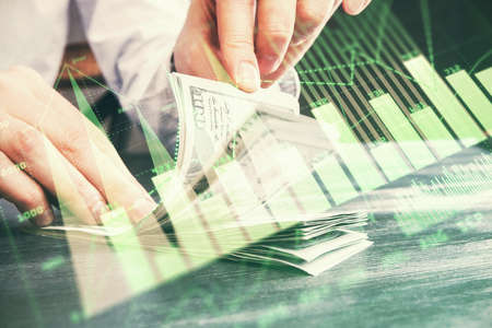 Multi exposure of forex graph drawing hologram and USA dollars bills and man hands. Technical...