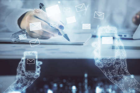 E-mail envelop theme hologram over hands taking notes background. Concept of electronic mail. Double exposureの写真素材