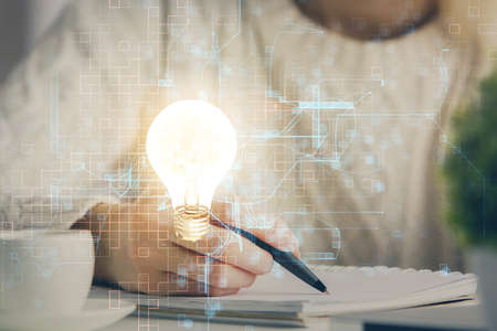 Drawing bulb over womans hands taking notes background. Concept of idea. Double exposureの写真素材