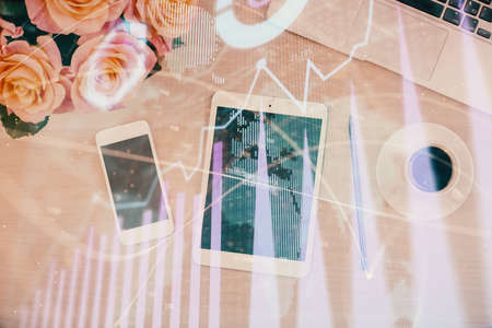 Double exposure of forex graph hologram over desktop with phone. Top view. Mobile trade platform concept.の写真素材