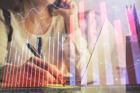 Double exposure of woman hands typing on computer and financial graph hologram drawing. Stock market analysis concept.の写真素材