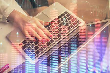 Double exposure of woman hands typing on computer and financial graph hologram drawing. Stock market...