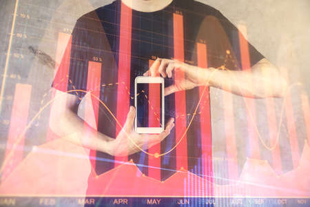 Double exposure of mans hands holding and using a digital device and forex graph drawing. Financial...