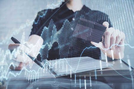 Double exposure of man hands holding a credit card and Forex graph drawing. Stock trading and digital fintech in Internet E-commerce concept.の写真素材