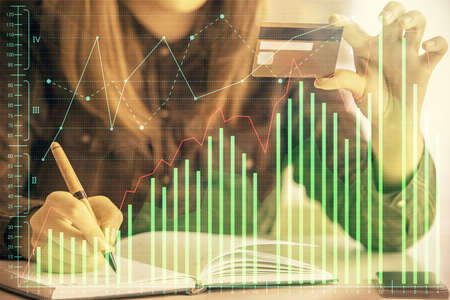 Multi exposure of woman on-line shopping holding a credit card and financial graph drawing. Stock...