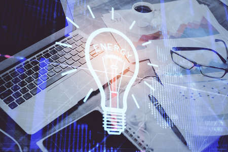 Computer on desktop in office with bulb icon hologram. Double exposure. Concept of idea.の写真素材