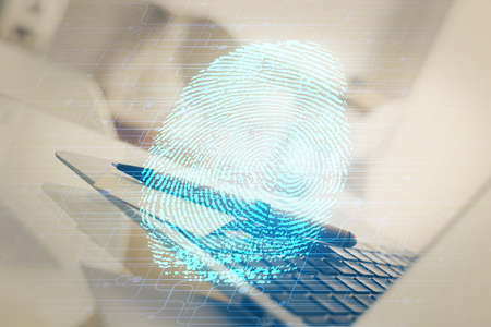 Computer on desktop in office with finger print drawing. Double exposure. Concept of business data security.の写真素材