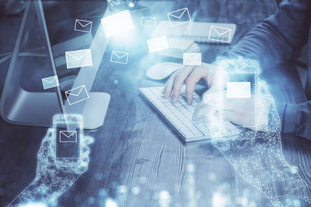 Envelop hologram drawing with businessman working on computer on background. Electronic mail...