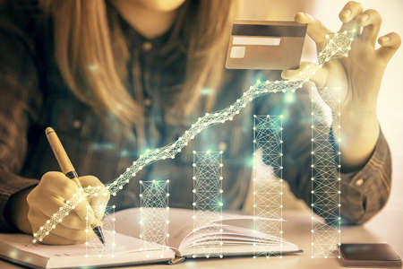 Multi exposure of woman on-line shopping holding a credit card and financial graph drawing. Stock...