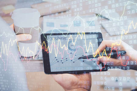 Double exposure of mans hands holding and using a phone and financial chart drawing. Market analysis...