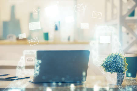 Desktop computer background in office and flying envelops hologram drawing. Double exposure. Electronic mail concept.の写真素材