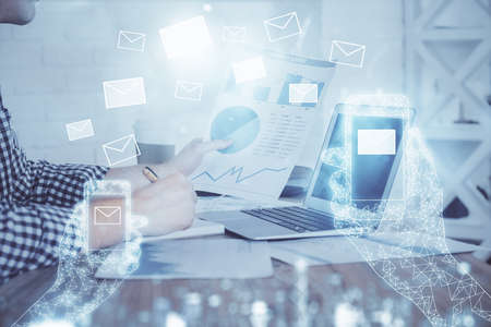 Envelop hologram drawing with businessman working on computer on background. Electronic mail...