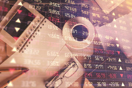Double exposure of financial graph hologram over desktop with phone. Top view. Mobile trade platform...