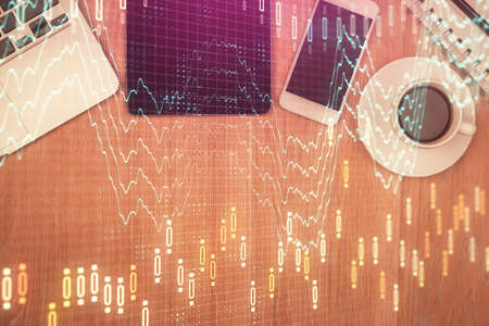 Double exposure of financial chart hologram over desktop with phone. Top view. Mobile trade platform...