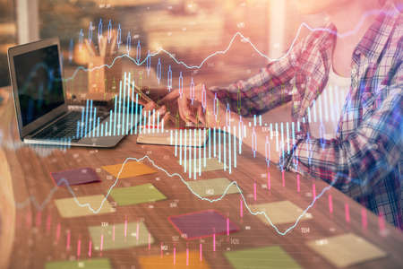 Double exposure of businesswoman hands typing on computer and forex graph hologram drawing....