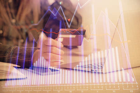 Multi exposure of woman on-line shopping holding a credit card and financial graph drawing. Stock...
