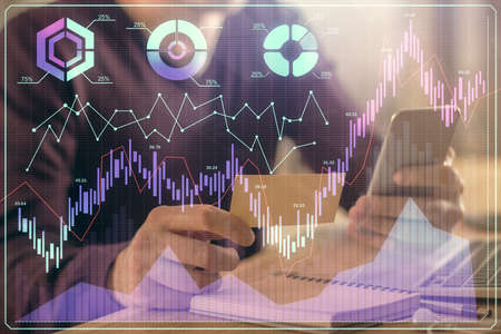 Double exposure of mans hands holding and using a phone and financial graph drawing. Analysis...