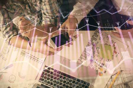 Double exposure of forex graph drawing and man and woman working together holding and using a mobile...