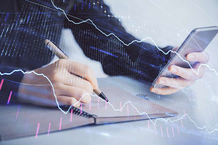 Double exposure of forex graph sketch hologram and woman holding and using a mobile device. Stock...