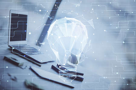 Computer on desktop in office with bulb icon hologram. Double exposure. Concept of idea.の写真素材