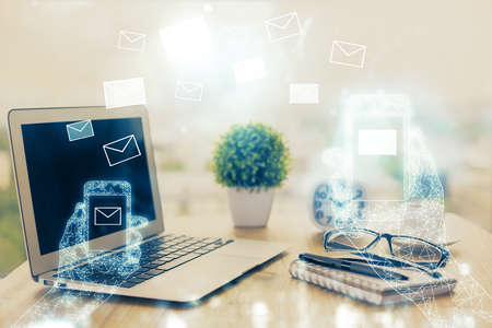 Desktop computer background in office and flying envelops hologram drawing. Double exposure. Electronic mail concept.の写真素材