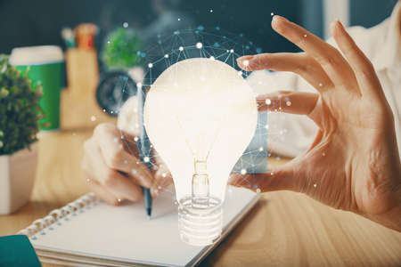 Drawing bulb over womans hands taking notes background. Concept of idea. Double exposureの写真素材