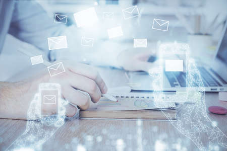 Envelop hologram drawing with businessman working on computer on background. Electronic mail...