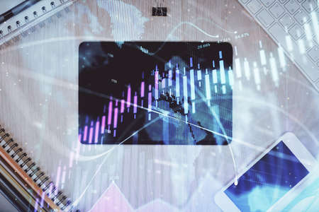 Double exposure of forex graph hologram over desktop with phone. Top view. Mobile trade platform...