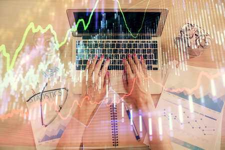 Double exposure of woman hands working on computer and forex graph hologram drawing. Top View....
