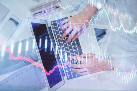 Double exposure of woman hands working on computer and forex graph hologram drawing. Top View....