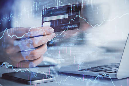 Multi exposure of woman on-line shopping holding a credit card and financial graph drawing. Stock...