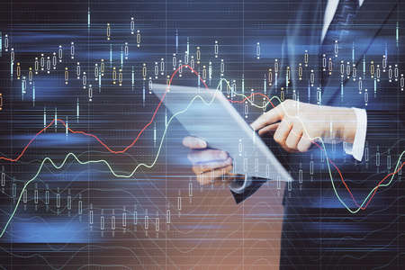 Double exposure of mans hands holding and using a digital device and forex graph drawing. Financial...