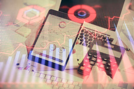 Double exposure of mans hands holding and using a digital device and forex graph drawing. Financial...