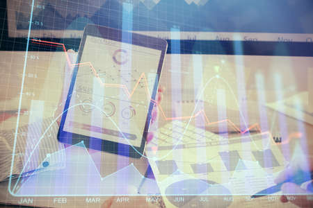 Double exposure of mans hands holding and using a digital device and forex graph drawing. Financial...
