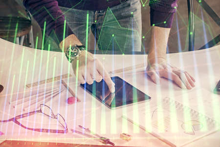 Double exposure of mans hands holding and using a digital device and forex graph drawing. Financial...