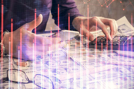 Double exposure of mans hands holding and using a digital device and forex graph drawing. Financial...