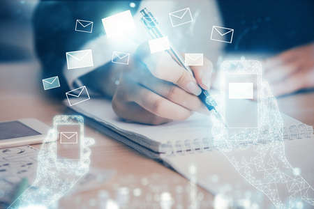 E-mail envelop theme hologram over hands taking notes background. Concept of electronic mail. Double...