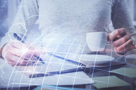 Double exposure of hands making notes with world map hologram and data theme icons. Concept of...